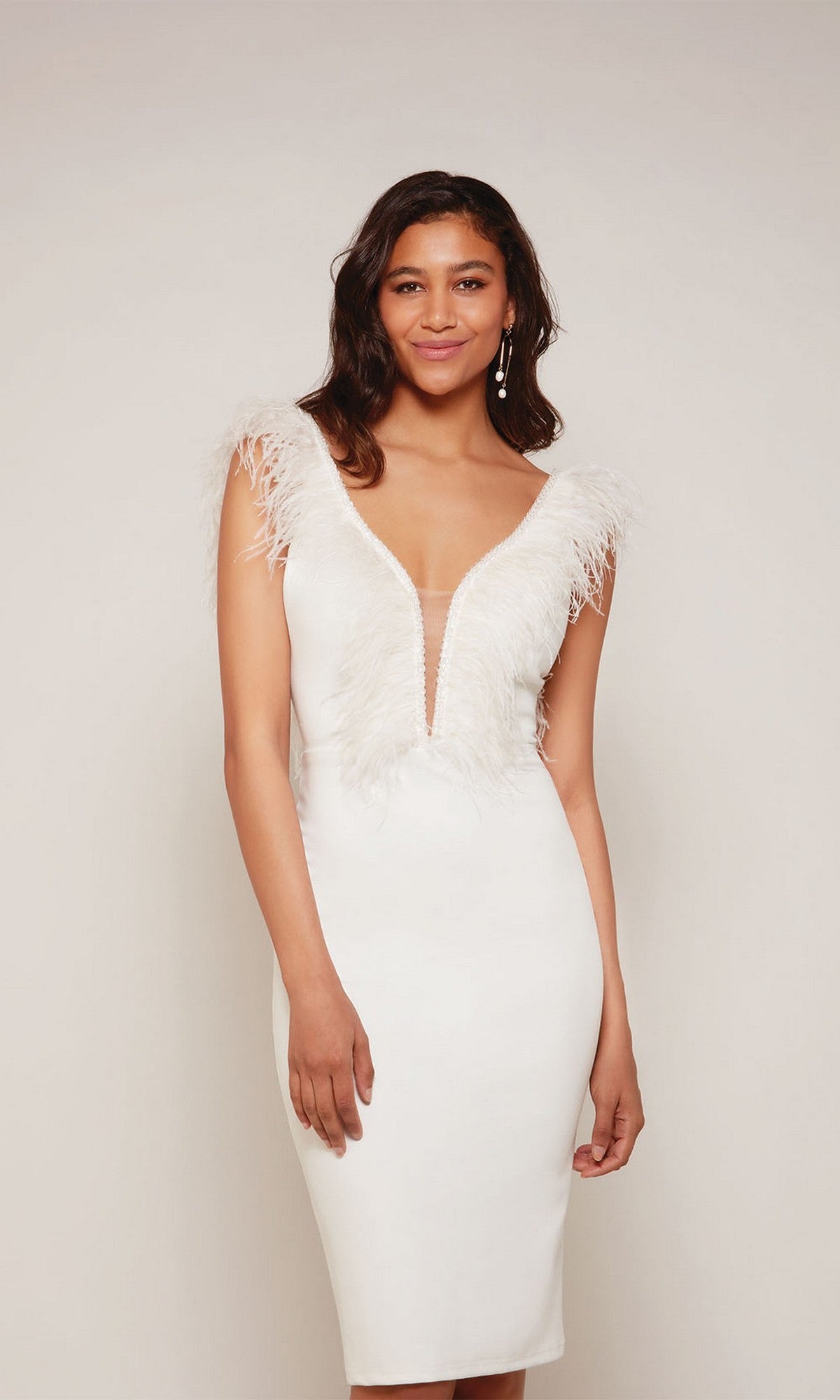 A woman stands against a neutral background wearing the Alyce 70033 knee-length semi-formal dress in diamond white, featuring feather accents on the shoulders and bust.